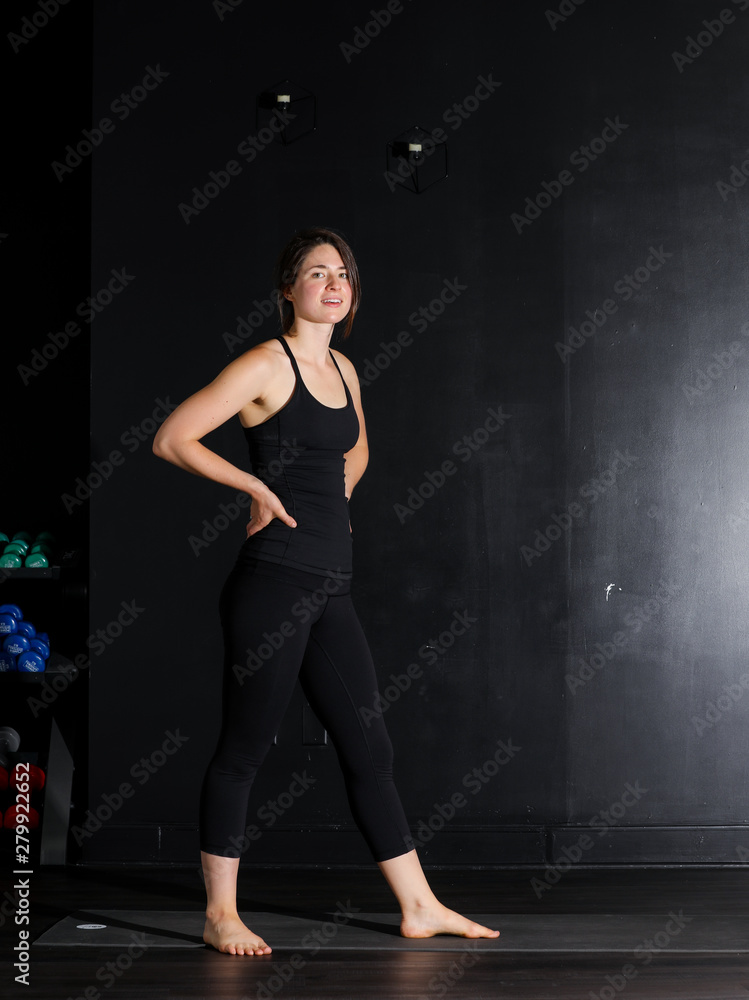Young white woman does yoga poses in a studio. 