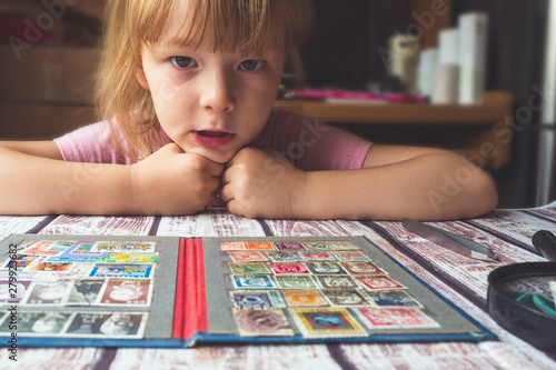portrait of a little girl looking postage stamps on the table
