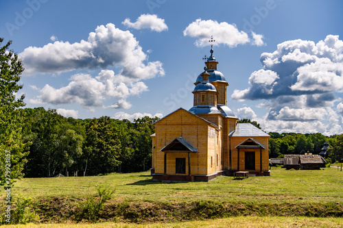 Ancient wooden church (18th century) on the background of great clouds on a blue sky. Pyrogiv, Ukraine. photo