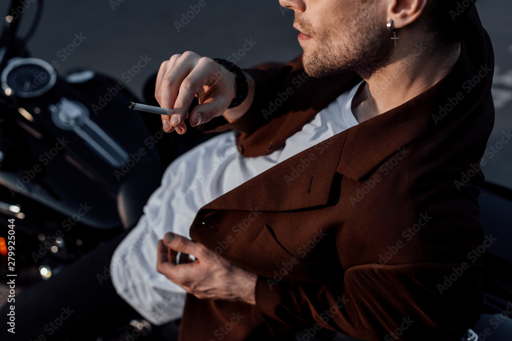 cropped view of man smoking cigarette while sitting on motorcycle cropped view of man smoking cigarette while sitting on motorcycle