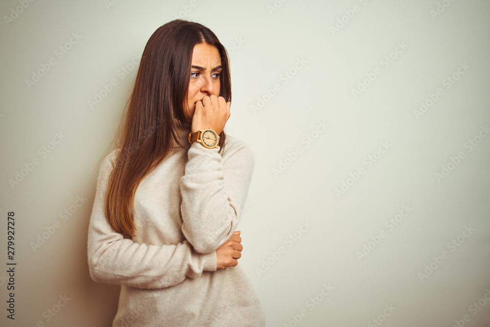 Young beautiful woman wearing winter turtleneck sweater over isolated white background looking stressed and nervous with hands on mouth biting nails. Anxiety problem.