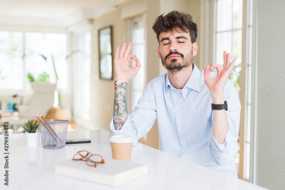 Young business man working relax and smiling with eyes closed doing meditation gesture with fingers. Yoga concept. Young business man working relax and smiling with eyes closed doing meditation gesture with fingers. Yoga concept.