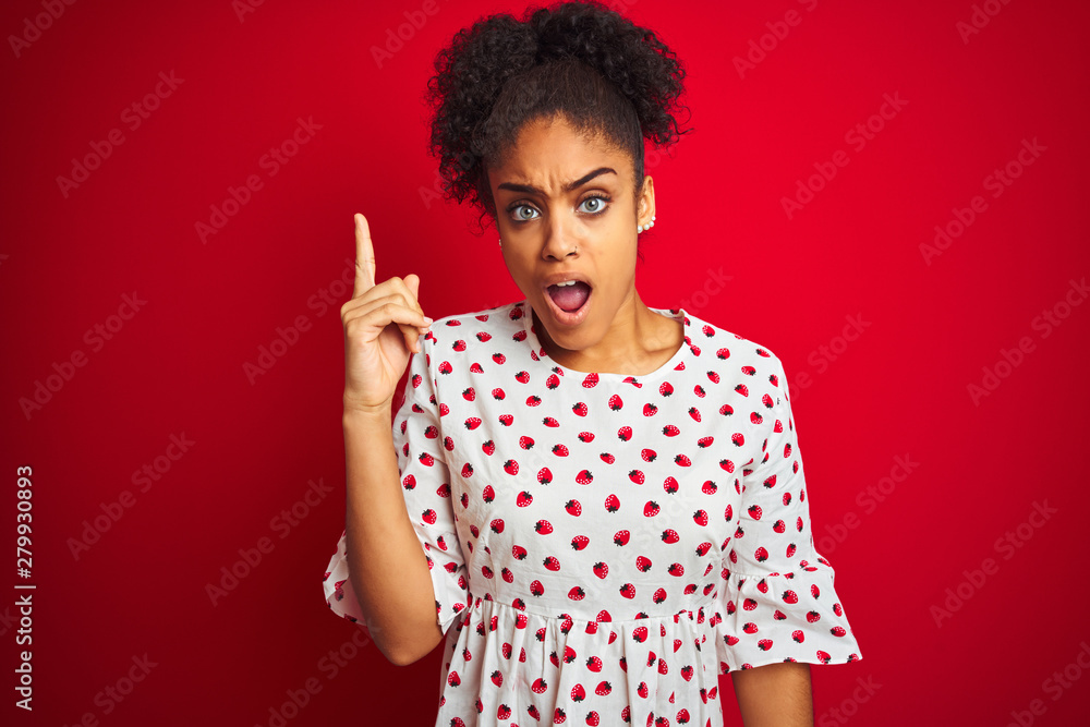 African american woman wearing fashion white dress standing over isolated red background pointing finger up with successful idea. Exited and happy. Number one. African american woman wearing fashion white dress standing over isolated red background pointing finger up with successful idea. Exited and happy. Number one.