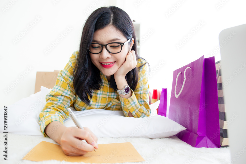 Beautiful Asian young woman writing a letter in the living room. Beautiful Asian young woman writing a letter in the living room.