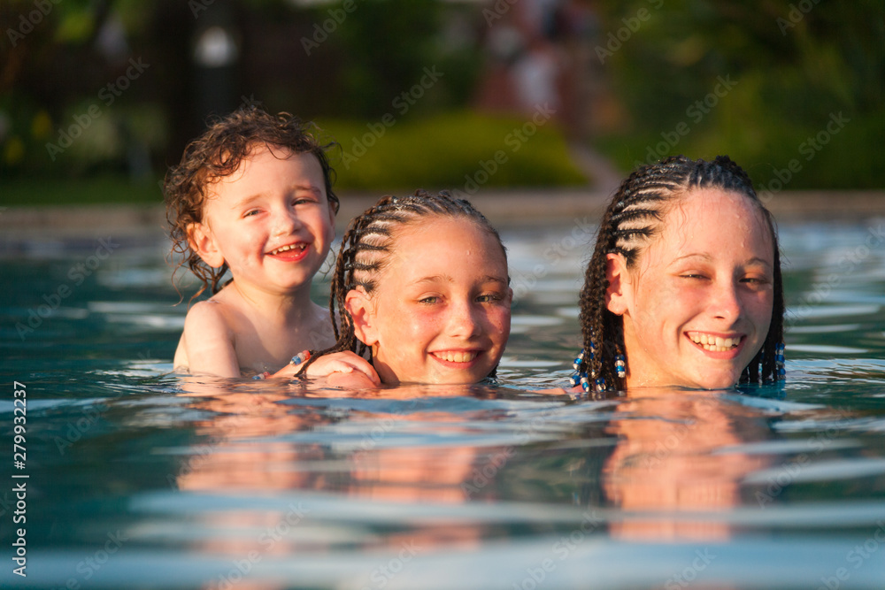 Three children playing piggyback while swimming in a pool in Cruz Bay, St. John, USVI