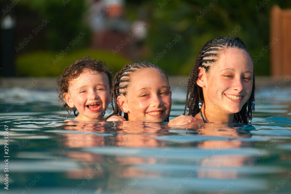 Three children playing piggyback while swimming in a pool in Cruz Bay, St. John, USVI Three children playing piggyback while swimming in a pool in Cruz Bay, St. John, USVI
