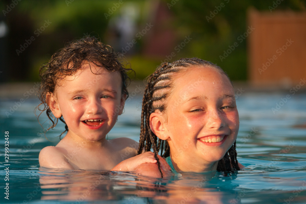 Little boy getting a piggyback ride from older girl while swimming in a pool at a resort in Cruz Bay, St. John, USVI Little boy getting a piggyback ride from older girl while swimming in a pool at a resort in Cruz Bay, St. John, USVI
