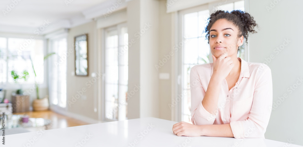 Wide angle of beautiful african american woman with afro hair looking confident at the camera smiling with crossed arms and hand raised on chin. Thinking positive. Wide angle of beautiful african american woman with afro hair looking confident at the camera smiling with crossed arms and hand raised on chin. Thinking positive.