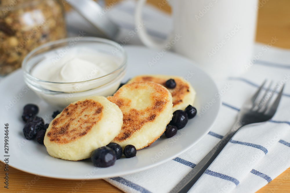 eastern european breakfast, fried circular syrniki, tvorozhniki or cheese cake with sour cream and hot drink on wooden table, close up view from above of horizontal still life stock photo image eastern european breakfast, fried circular syrniki, tvorozhniki or cheese cake with sour cream and hot drink on wooden table, close up view from above of horizontal still life stock photo image