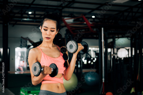 sport woman at fitness gym club doing exercise for arms with dumbbells and showing muscle bodybuilding, fitness concept, sport concept © I Believe I Can Fly