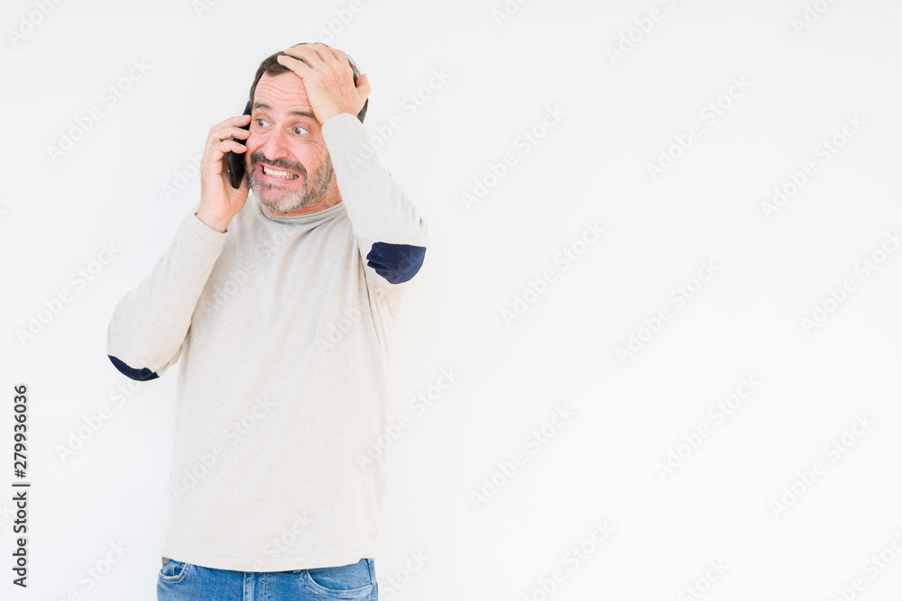 Senior man talking on smartphone over isolated background stressed with hand on head, shocked with shame and surprise face, angry and frustrated. Fear and upset for mistake. Senior man talking on smartphone over isolated background stressed with hand on head, shocked with shame and surprise face, angry and frustrated. Fear and upset for mistake.