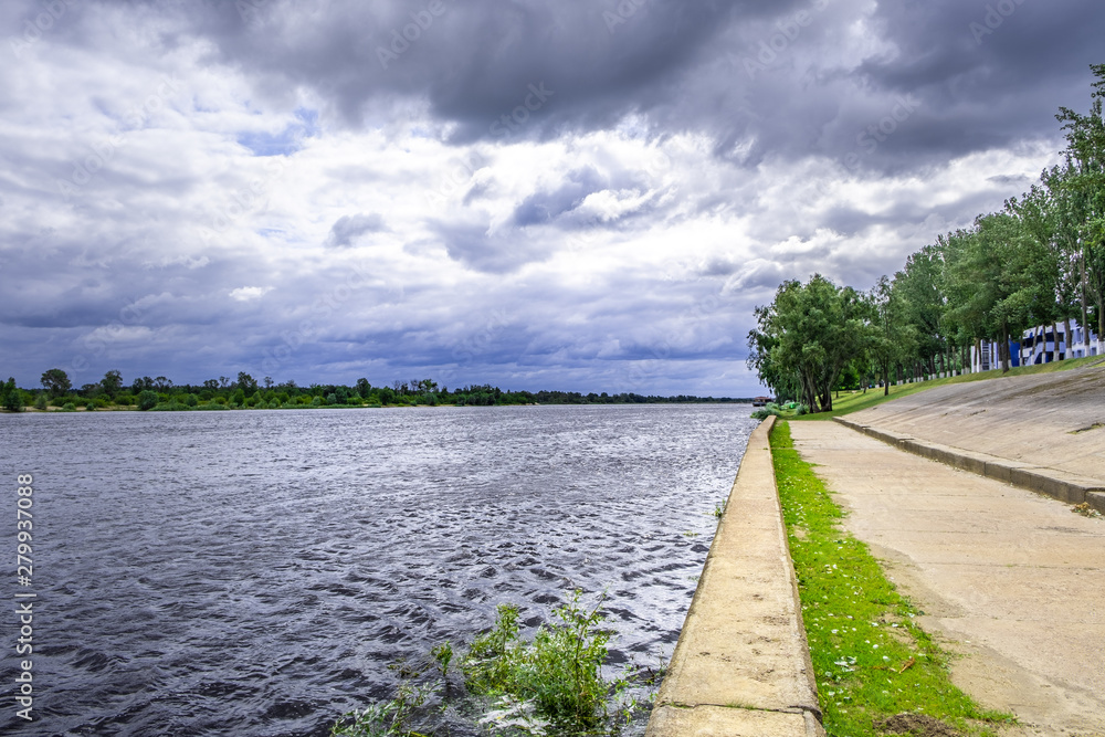 Pripyat river under gloomy stormy sky with walking path on its bank