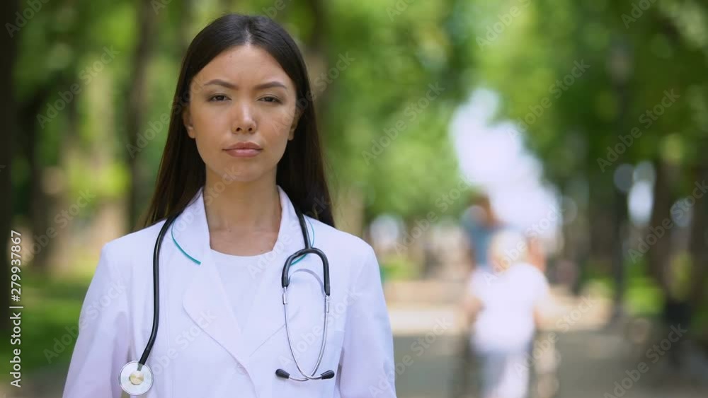Serious female doctor looking into camera at rehabilitation center park, health Serious female doctor looking into camera at rehabilitation center park, health