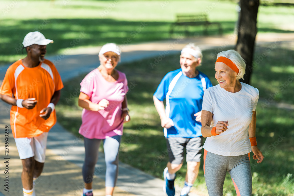selective focus of happy retired woman running with multicultural pensioners in park selective focus of happy retired woman running with multicultural pensioners in park