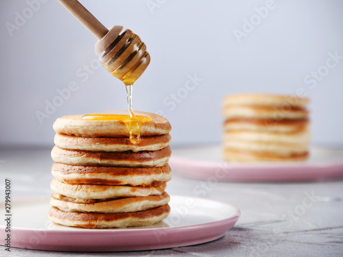 Stack of Pancakes with pouring honey. decorating concept on light background