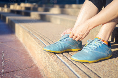 Running shoes - woman tying shoe laces. Closeup of female sport fitness runner getting ready for jogging outdoors.
