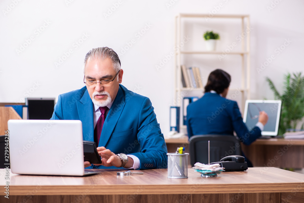 Young and old employees working together in the office Young and old employees working together in the office