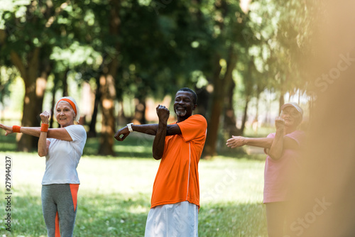 selective focus of happy milticultural retired women and man working out in park