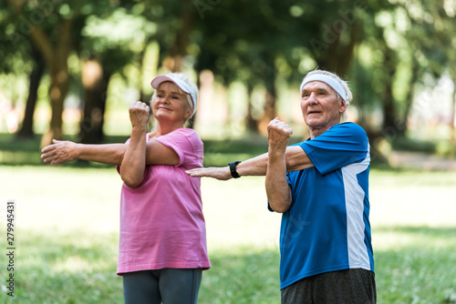 happy retired couple doing exercises while standing in park