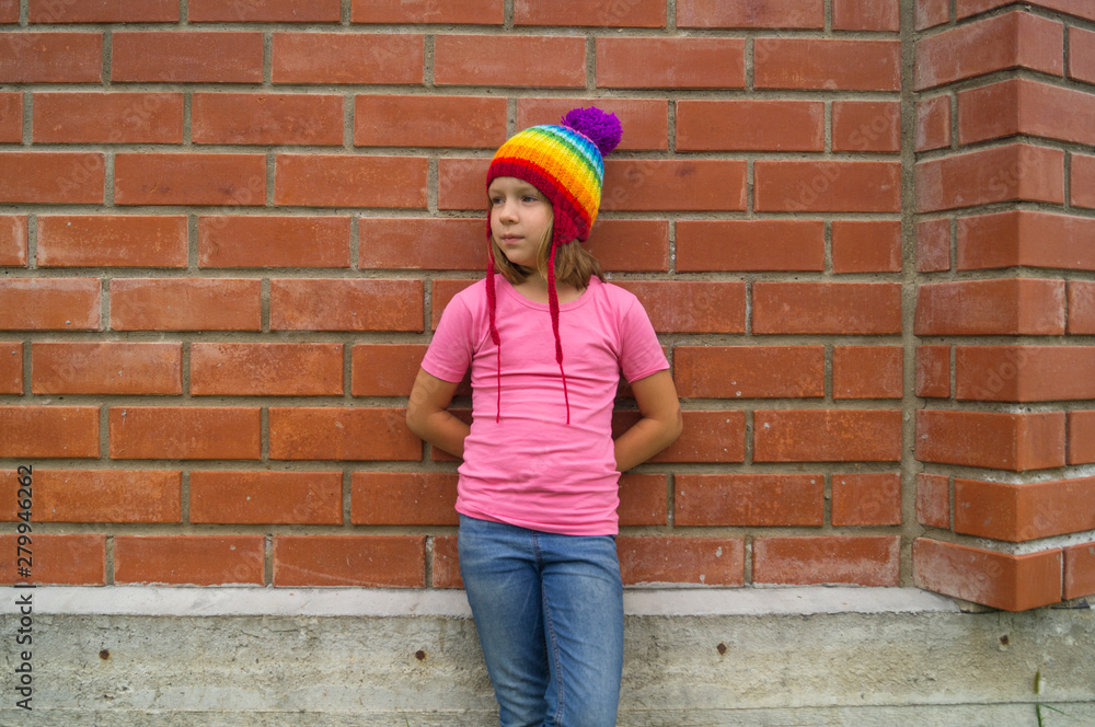 girl in rainbow knitted hat on a brick background. girl in rainbow knitted hat on a brick background.