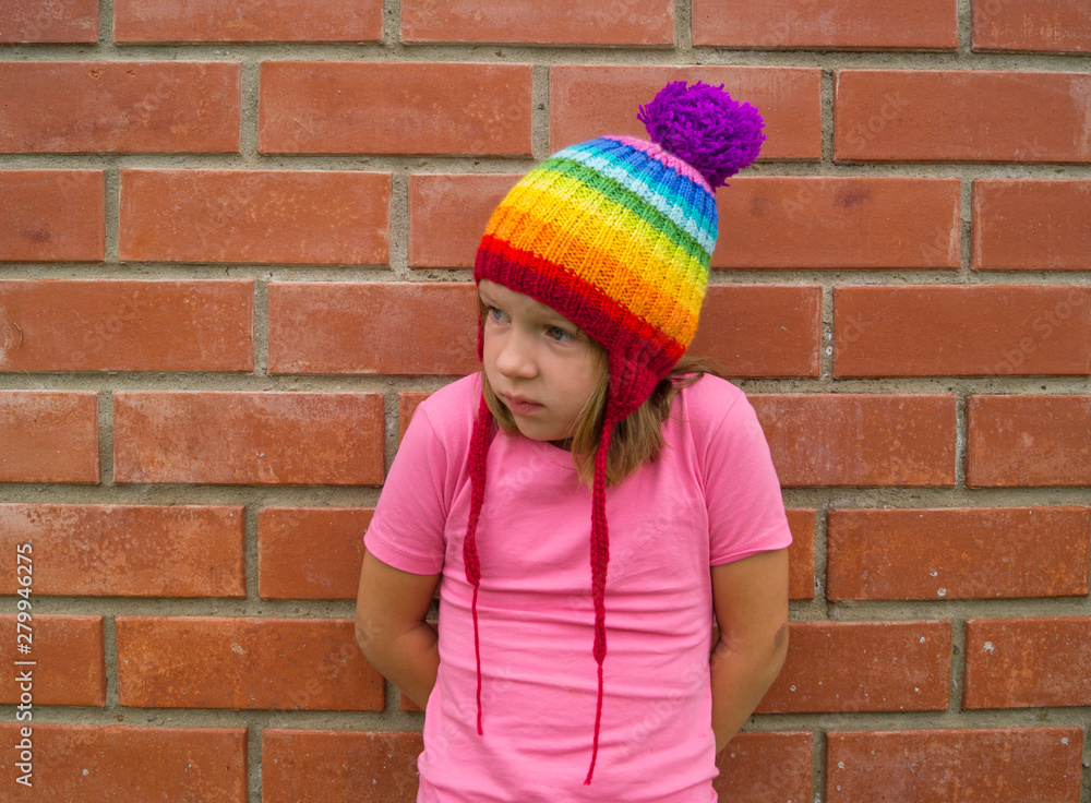 girl in rainbow knitted hat on a brick background. girl in rainbow knitted hat on a brick background.