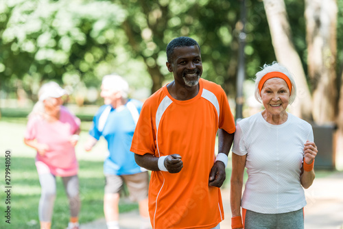 selective focus of african american senior man and retired woman exercising near pensioners outside
