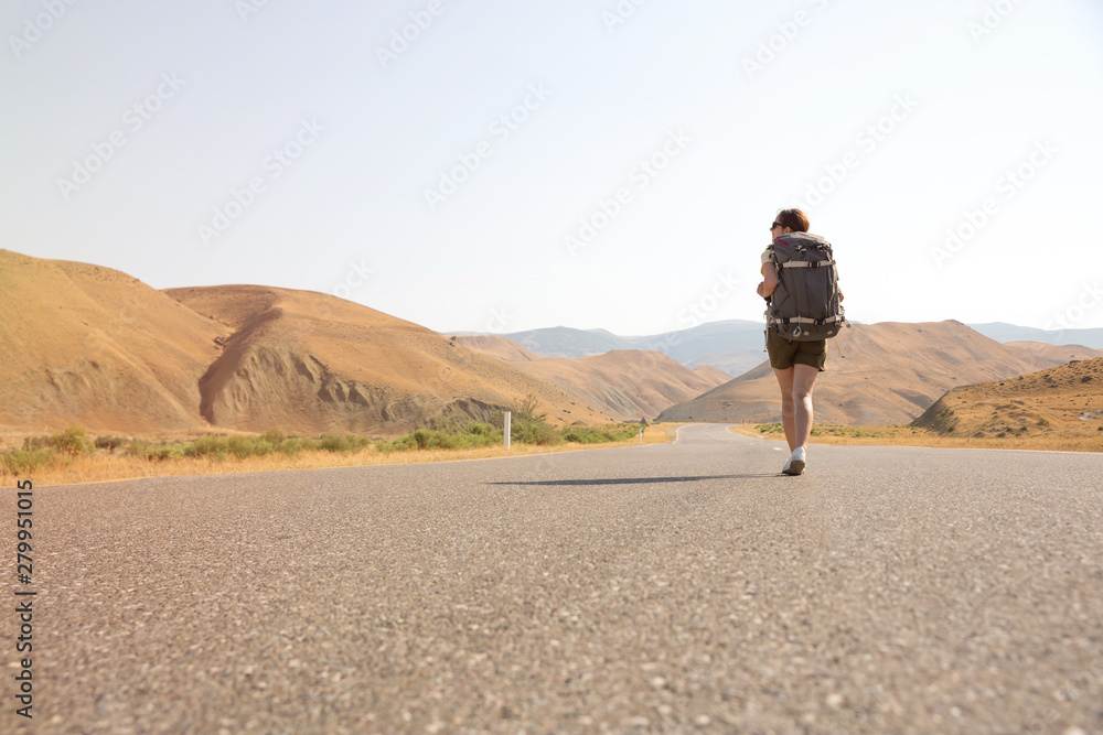 Hitchhiker traveler woman on the road in sunset. Girl traveler hiker on the road. Summer vacation. Freedom. Hitchhiker traveler woman on the road in sunset. Girl traveler hiker on the road. Summer vacation. Freedom.