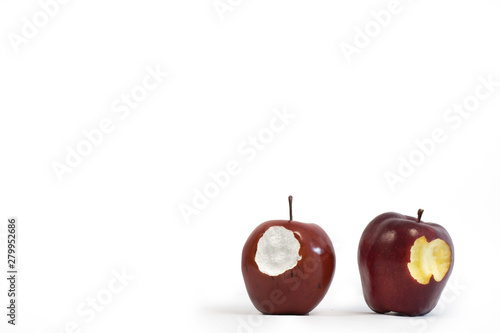 Fake styrofoam apple next to a real apple with bites taken from both against white background with copy space. 
