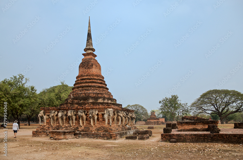 Fototapeta premium Ruins of Temple Wat Chang Lom on the territory of famous Sukhothai Historical Park, a UNESCO World Heritage Site, unique architectural elements in the form of elephants, Thailand