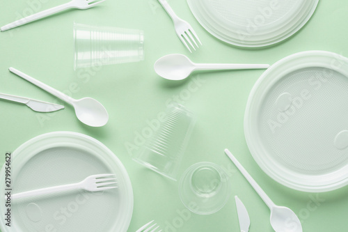 Various white plastic disposable tableware on green background. photo