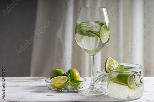 Mojito cocktail with mint and lime with ice in a large glass on a high stem and in a jar