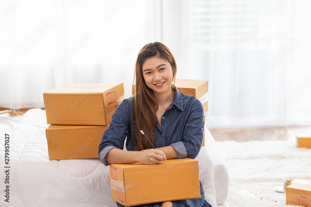 SME entrepreneur of Young women working with laptop and writing customer address for send order Online shopping at home,Cheerful and Happy with box for packaging in home,Startup and Freelance Concept SME entrepreneur of Young women working with laptop and writing customer address for send order Online shopping at home,Cheerful and Happy with box for packaging in home,Startup and Freelance Concept