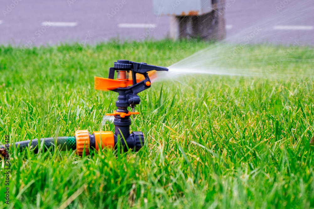 Sprinkler. Automatic irrigation system on the background of green grass. Lawn watering system. Freshness concept