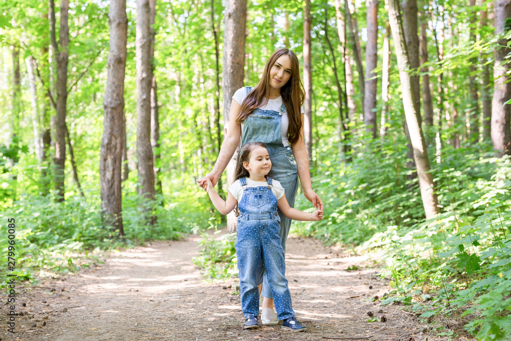Family, nature and people concept - Mother and cute little daughter spend time together on a walk in the forest Family, nature and people concept - Mother and cute little daughter spend time together on a walk in the forest