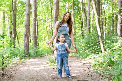 Family, nature and people concept - Mother and cute little daughter spend time together on a walk in the forest