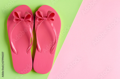 Pink rubber slippers on green background composition.
