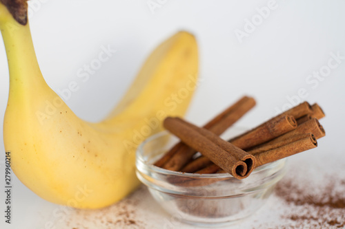 banana and cinnamon sticks in a bow on white background
