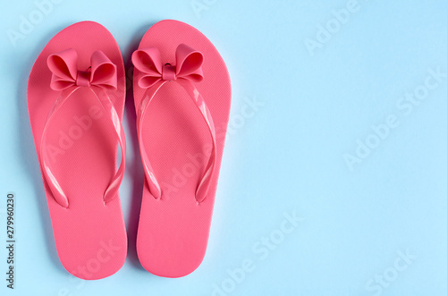 Pink rubber slippers on blue background composition.