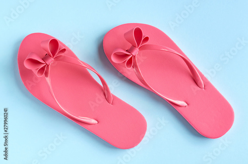 Pink rubber slippers on blue background composition.