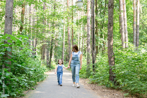 Fototapeta Naklejka Na Ścianę i Meble -  Family, nature, people concept - Young mother and cute daughter spend time together on a walk in the forest