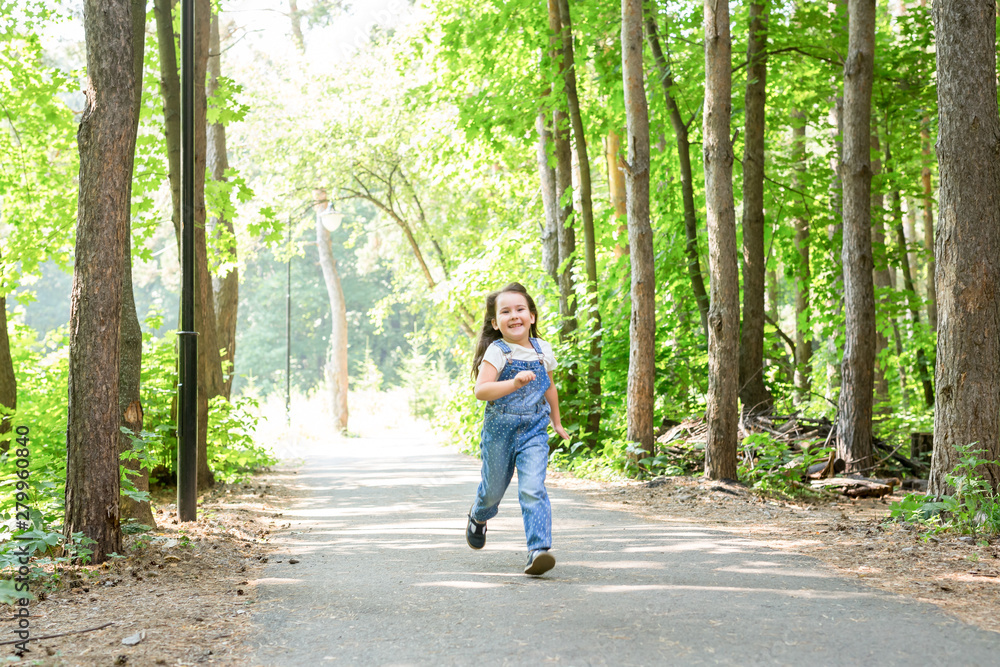 Children, childhood and nature concept - Portrait of beautiful small child girl running through the park