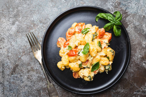 Homemade italian gnocchi with tomato, garlic, basil and mozzarella cheese on stone background. Top view. Copy space.