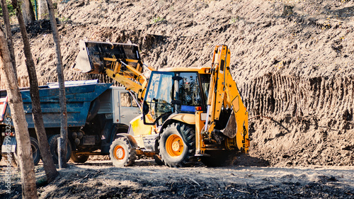 Wallpaper Mural small yellow excavator fills the ground with an orange truck Torontodigital.ca