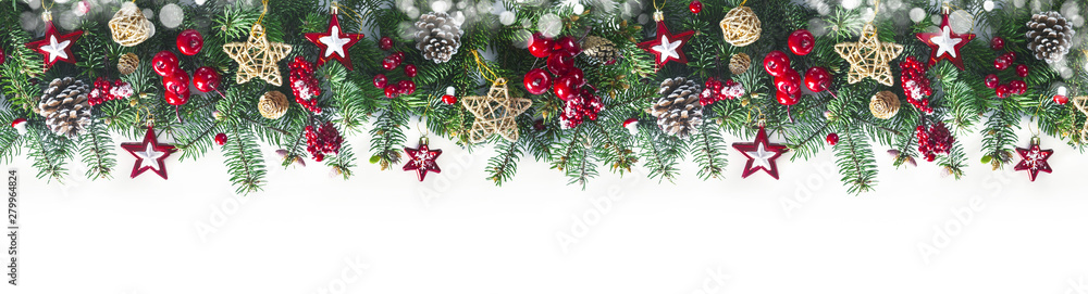 Festive Christmas border, isolated on white background. Fir green branches are decorated with gold stars, fir cones and red berries, close-up.