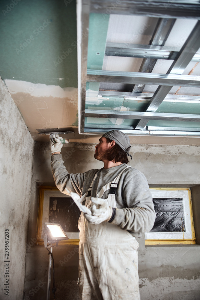 Fototapeta premium Construction worker plastering gypsum walls inside the house.