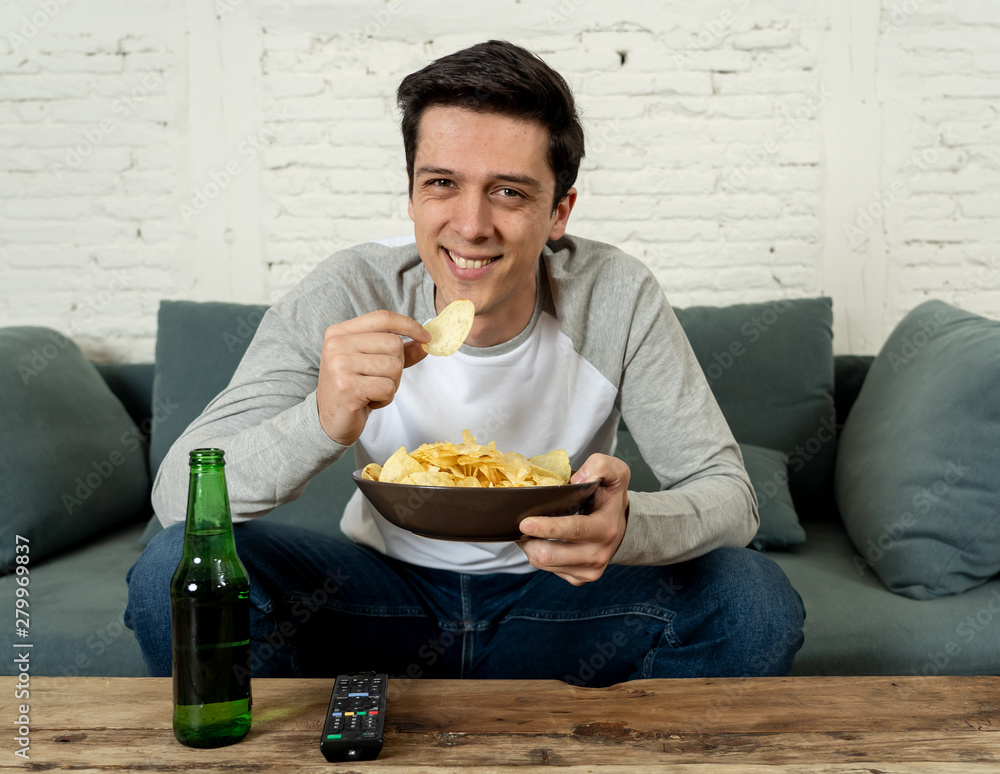 Excited and happy young man sitting on the couch watching TV. TV programming concept Excited and happy young man sitting on the couch watching TV. TV programming concept
