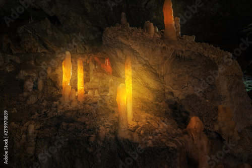 talagmites in the cave illuminated by yellow light