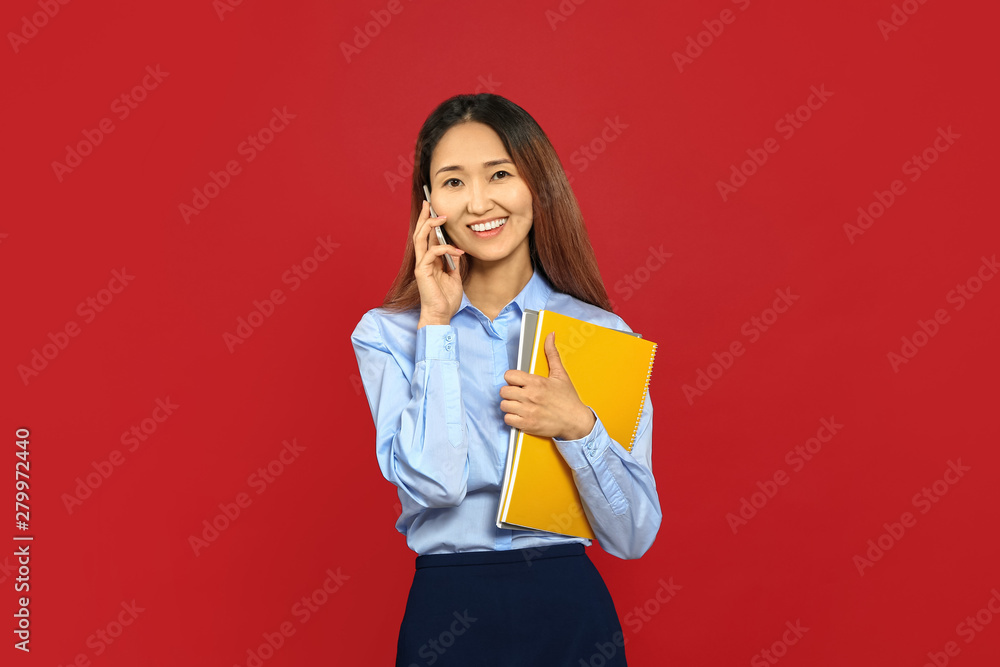 Asian businesswoman talking by mobile phone on color background Asian businesswoman talking by mobile phone on color background