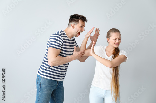 Young quarrelling couple on light background
