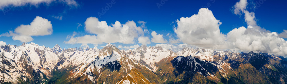 Panorama of snowy mountains. Beautiful landscape of wild nature. Clouds in the mountains